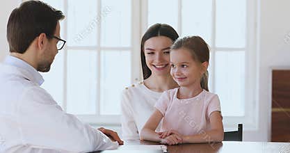 Qualified pediatrician consulting small patient with mom at checkup visit.