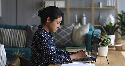 Concentrated millennial indian female college student woman doing university assignment.