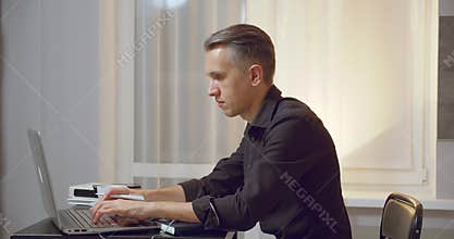 Business man reading documents and typing text or message on laptop at workplace