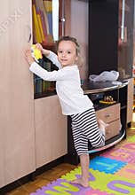 Little girl cleaning furniture with a sponge