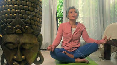 Home lifestyle - beautiful and happy mature woman with gray hair on her 50s doing yoga meditation exercise at Asian deco bedroom
