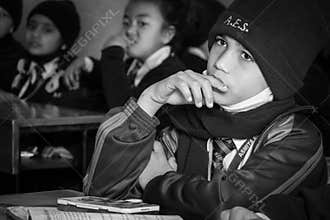 A Young Boy Sitting in School Looking Bored