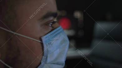 Male in medical mask watching breaking news about coronavirus at home