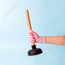 Hand in pink glove holding domestic plunger. Concept of cosmetology device for skin cleaning and home work day. Creative idea