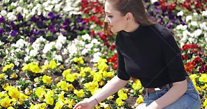 Side view of female in casual outfit sitting on side of flowerbed