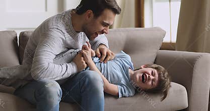 Affectionate young father tickling little laughing child son.
