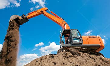 Excavator with metal tracks unloading soil at construction site