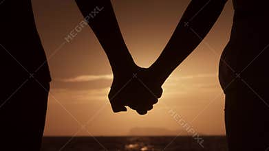 Close up silhouette man and woman touching hands together at sunset beach. Romantic couple couple holding each other
