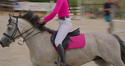 Competitive woman rider on horse jumping over obstacles, slow motion, equestrian competition outdoors. Training jumping