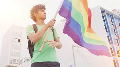 Smiling handsome young man with LGBT flag in his hands