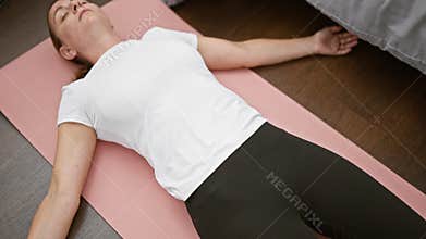 Serene blonde woman engaging in morning yoga, wholly absorbed in mindful breathing on mat in bedroom