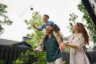Son plays with a baseball on dads shoulders