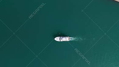 Top shot of slow motion drone shot of boat in waters near marina. Panning shot of boat swim and raise waves in waters.