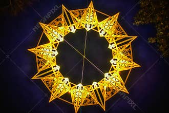 Yellow star (tetradecagon or fourteen sided polygon) made of bright light shining in the night sky. Tetrakaidecagon