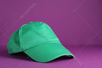 Baseball cap on purple background, space for text