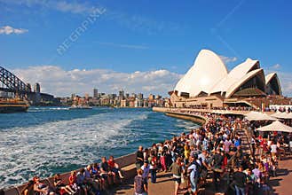 Busy large crowd with people eating, passing by, sunbathing & enjoying at Sydney Opera House, New South Wales NSW, Australia