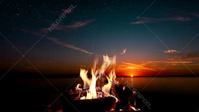 a bonfire burns at night against the background of mountains and sea with bright stars