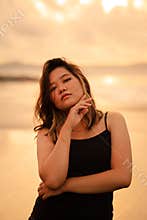 An Asian woman in a black dress with a very sexy expression attracts the attention of people around the beach