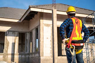 A worker wearing fall protection safety clothing  with hooks at construction site. Safety body construction, Working at height