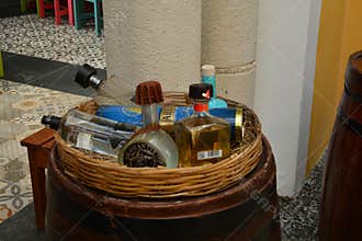 Basket of Liquor Bottles on Barrel in Colorful Mexican Setting