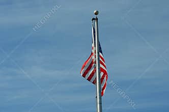 American Flag Waving on Flagpole Against Blue Sky