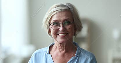 Serious pretty blonde senior woman wearing stylish round glasses