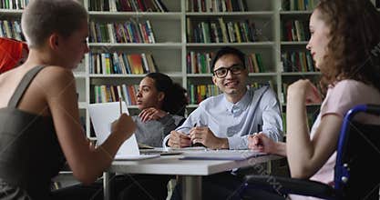 Diverse students take part in teamwork seated in library
