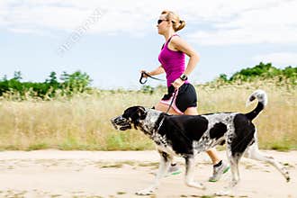 Woman runner running, walking dog in summer nature