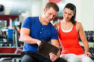 Woman and Personal Trainer in gym, with dumbbells