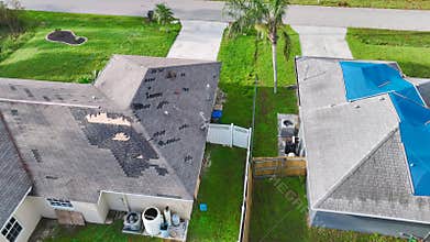 Top view of leaking house roof covered with protective tarp sheets against rain water leaks until replacement of asphalt