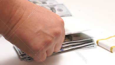 Woman's fingers, money tallying on tabletop. Depicting finance and accounting themes. A person is counting 100