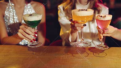 Friends, girls meeting in bar to celebrate holidays, birthday. Focus on cocktails, clinking glasses. Cheers. Christmas