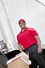 Cheerful young delivery person pushing handtruck