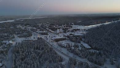 Aerial view of snowy forest trees and rural house in the evening in Levi village, Finland