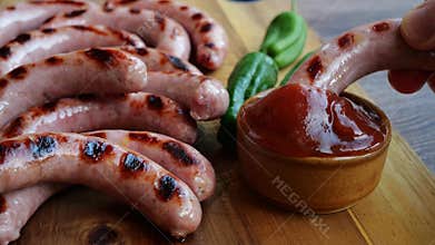 Natural sausages grill dipped in red sauce. Natural sausages grill on wood board. Close up.