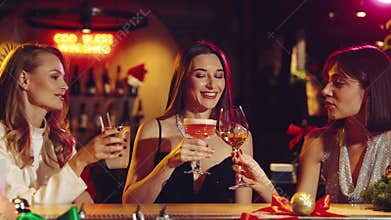 Three beautiful women in stylish dresses meeting in bar, drinking cocktails, talking about life, having fun and