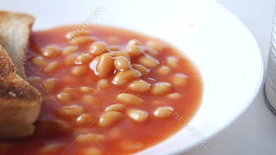 Tasty baked beans and bread on a plate on table