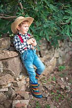 Happy kid boy little farmer holds a newborn baby chicken in his hands outdoor in the farm. Farm animals and farmland