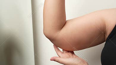 Asian oversize woman squeezing excess flabby fat of arm.