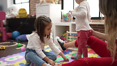 Teacher with girls playing with maths puzzle game and construction blocks at kindergarten