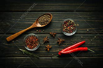 Two pods of red chili peppers and dry spices with coriander in a spoon on a dark vintage table prepared by the chef to add to food