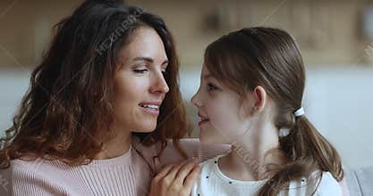 Little daughter whispers secrets on mothers ear