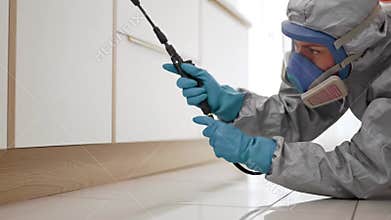 Pest Control Technician Spraying Insecticide in Kitchen