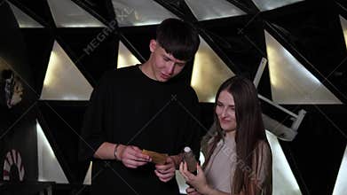 Two friends are reading a task on a note in a black and white dark quest room.
