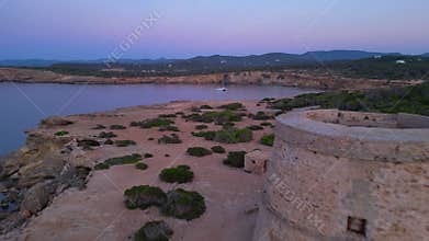 Old defense tower on cliff in Ibiza at sunset. Amazing aerial view flight drone
