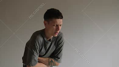 Young man experiencing stomach cramps on gray background. Digestive pain, health issue. Copy space.