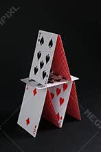 House of playing cards on black background