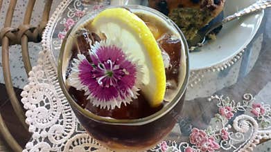 close up video of an orange Americano coffee served in a glass with a straw and flower decoration.