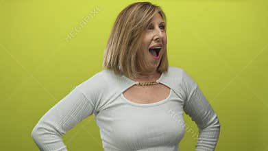Caucasian woman posing with hands on hips and open mouth expression in a bright green studio; surprise amazement