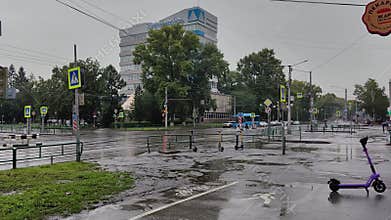 Rainy city scene with an intersection, pedestrians, electric scooters and buildings. Novokuznetsk. Russia. 2025